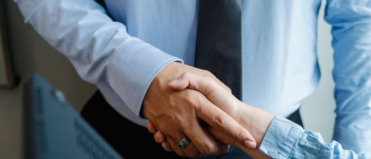 Male and female business partners in formal clothes shaking hands after successful deal.