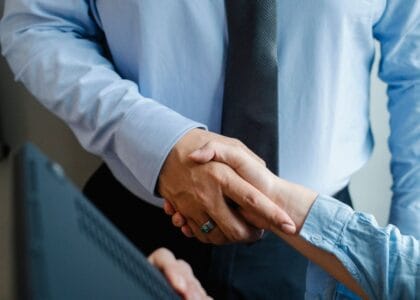 Male and female business partners in formal clothes shaking hands after successful deal.